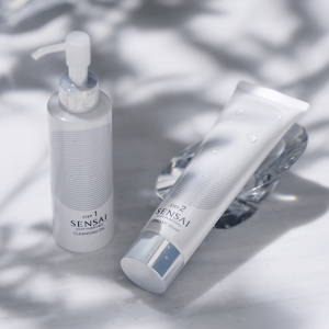 Silky Purifying Cleansing Oil and Creamy Soap bottles shown next to each other on white surface with mood lighting